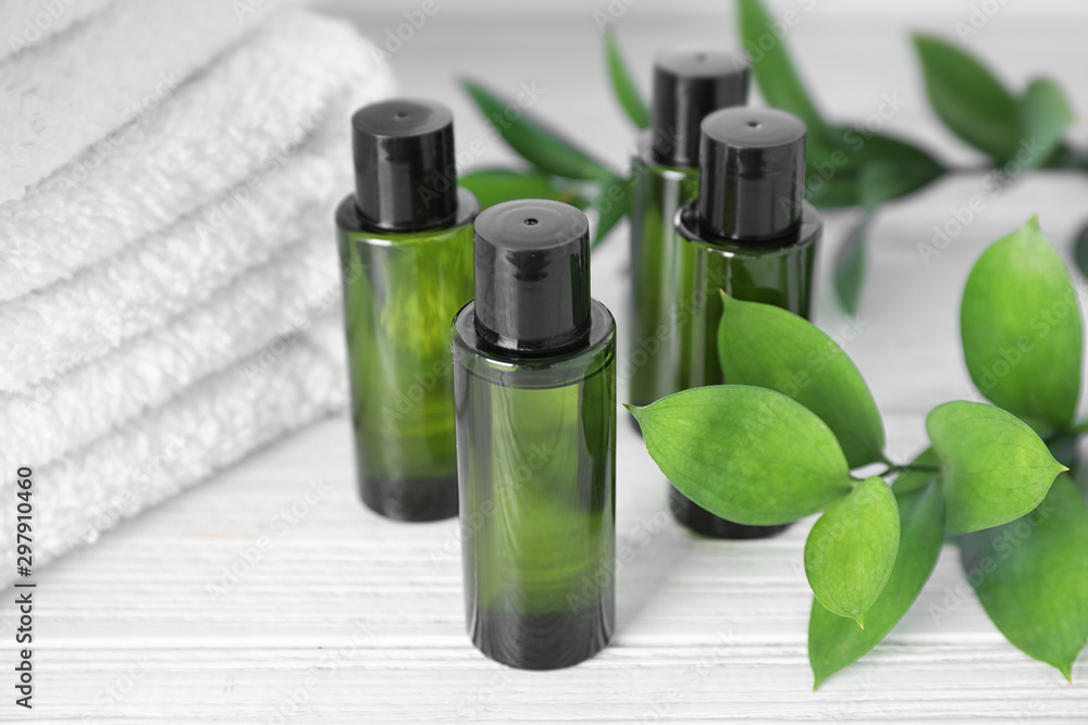 Mini bottles with cosmetic products and towels on white wooden table Mini bottles with cosmetic products and towels on white wooden table