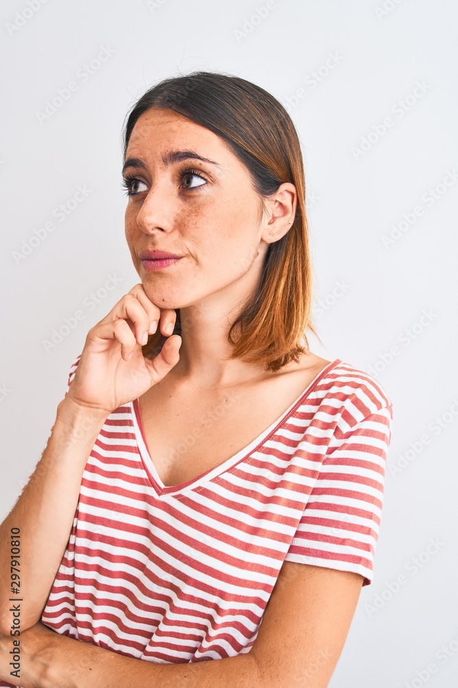 Beautiful redhead woman wearing casual striped red t-shirt over isolated background serious face thinking about question, very confused idea Beautiful redhead woman wearing casual striped red t-shirt over isolated background serious face thinking about question, very confused idea