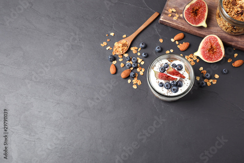 Healthy homemade granola with yogurt on dark grey table, flat lay. Space for text