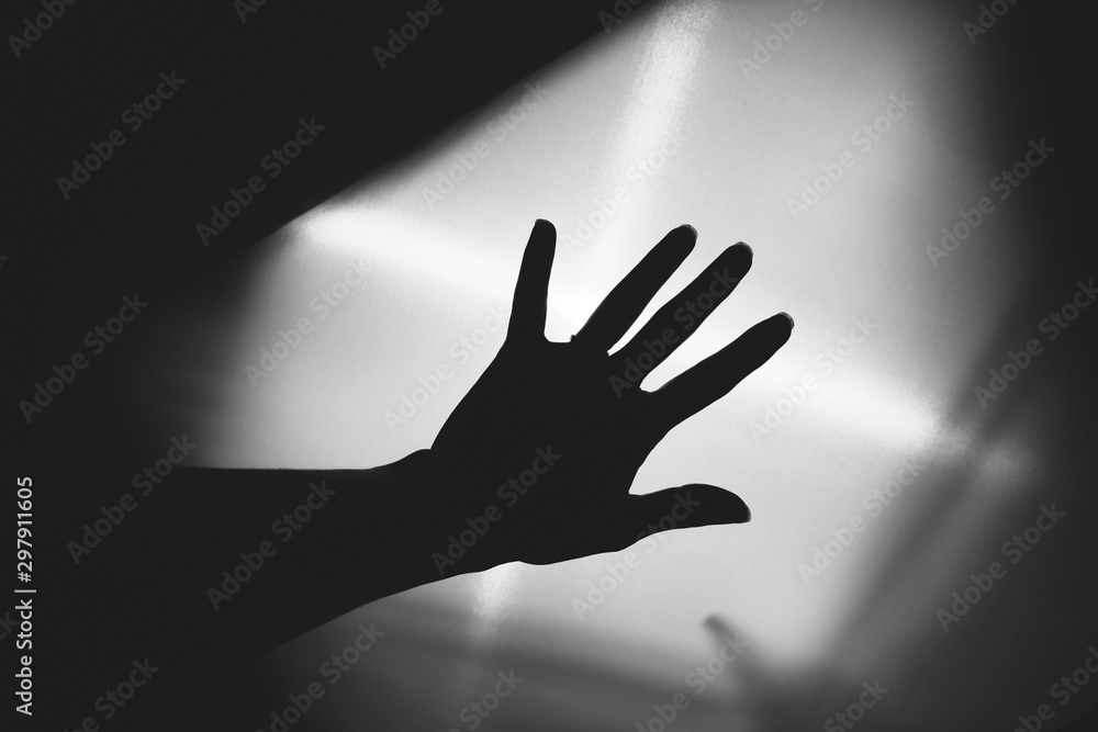Spooky hand silhouette over light for creepy Halloween concept.
