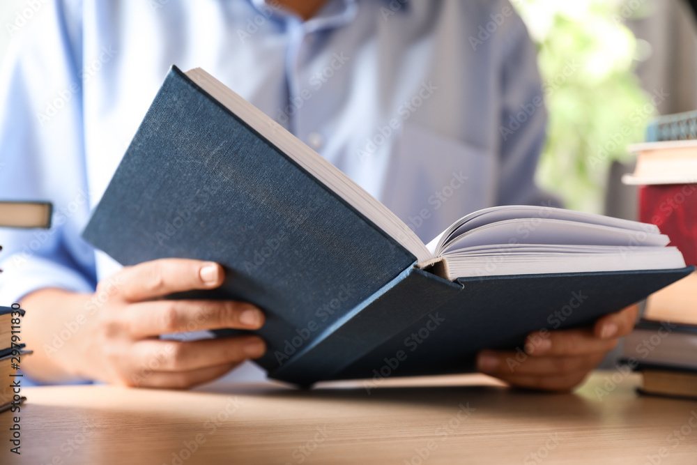 Woman reading hardcover book at wooden table indoors, closeup Woman reading hardcover book at wooden table indoors, closeup