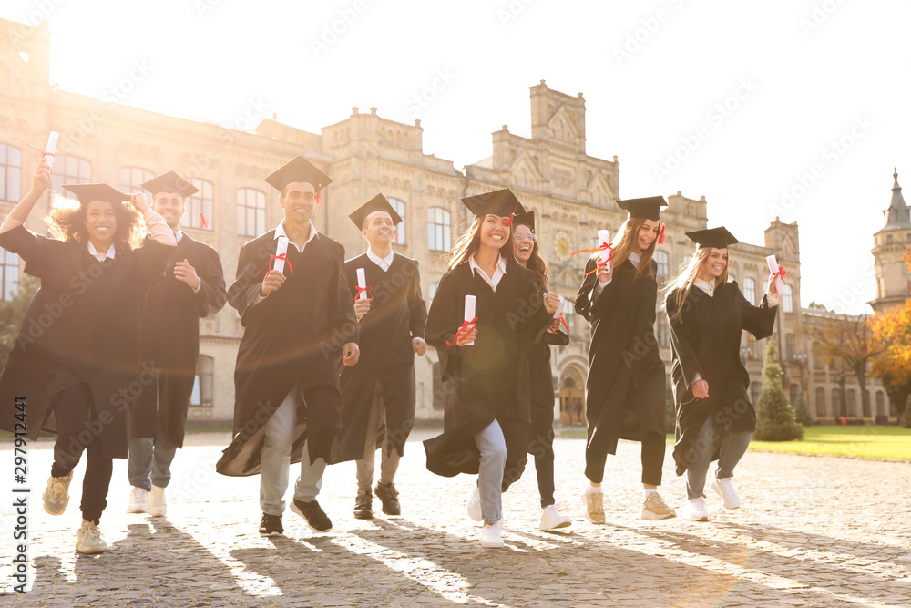 Naklejka premium Happy students with diplomas outdoors. Graduation ceremony
