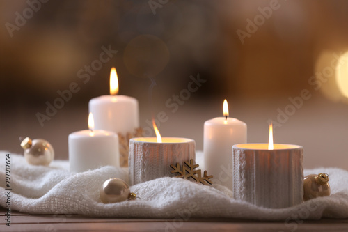 Composition with candles in ornate holder on wooden table against blurred background. Christmas decoration