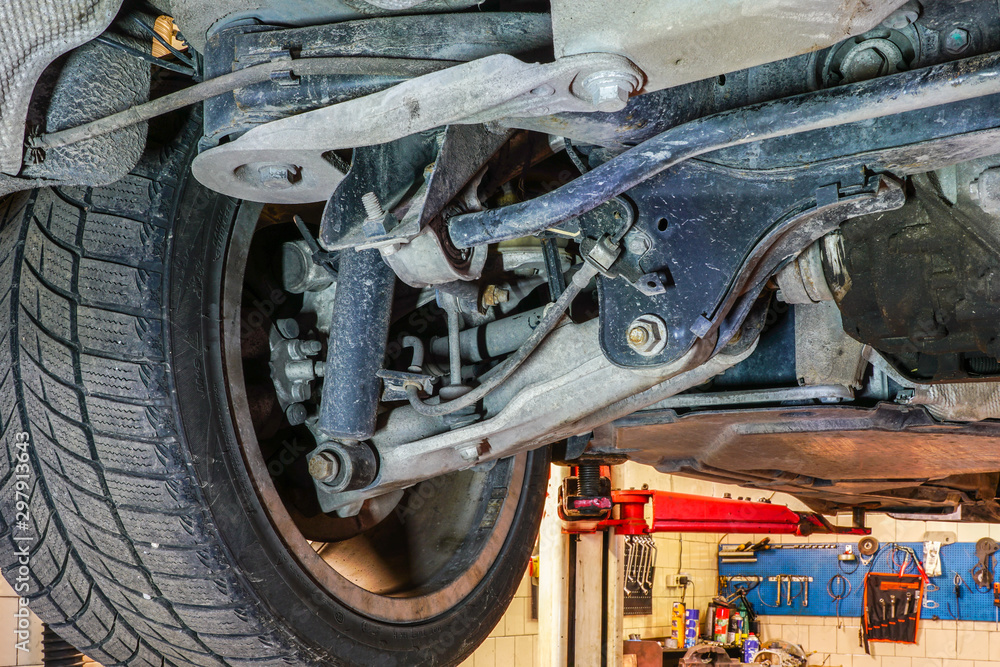 car wheel and suspension detail of lifted automobile at repair service station car wheel and suspension detail of lifted automobile at repair service station