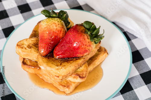 French toast with two strawberries and syrup