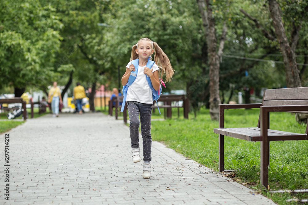 Child girl runs from school with a backpack. The concept of school, study, education, friendship.