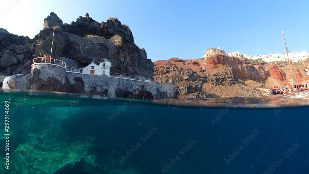Underwater and sea level photo of iconic islet and church of Agios Nikolaos below iconic village of Oia, Santorini island, Cyclades, Greece