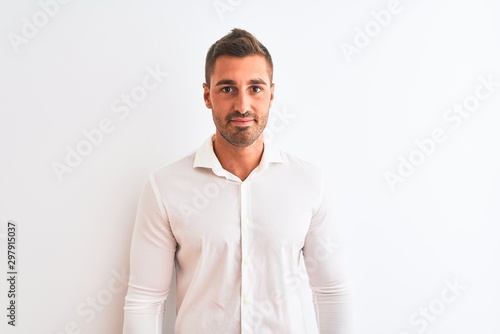 Young handsome business man wearing elegant shirt over isolated background Relaxed with serious expression on face. Simple and natural looking at the camera. © Krakenimages.com