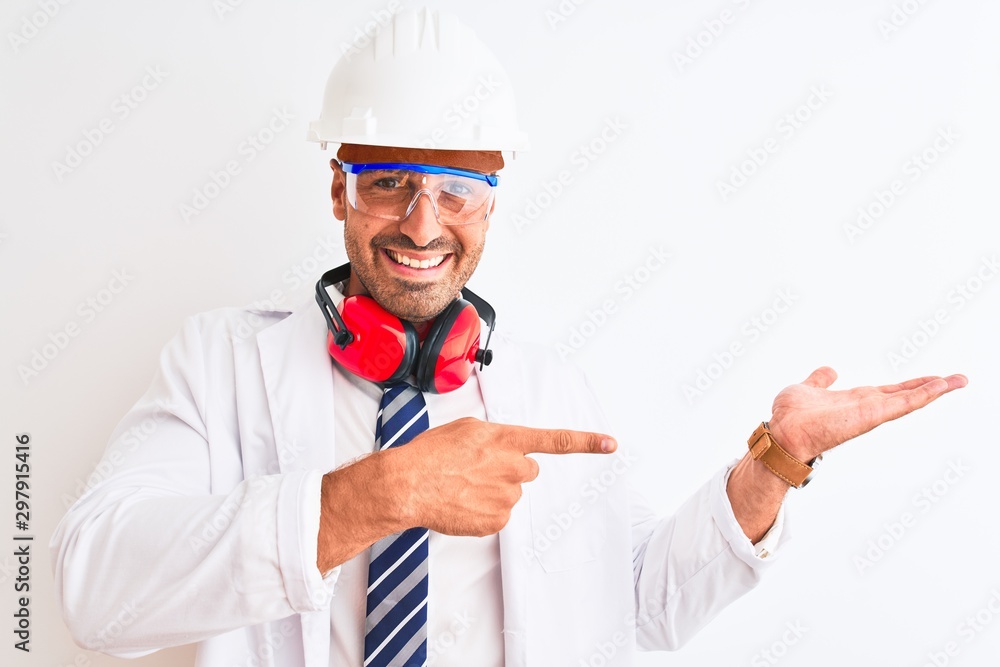 Young chemist man wearing security helmet and headphones over isolated background amazed and smiling to the camera while presenting with hand and pointing with finger.