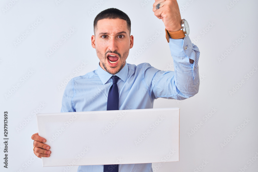 Young business man holding blank banner over isolated background annoyed and frustrated shouting with anger, crazy and yelling with raised hand, anger concept Young business man holding blank banner over isolated background annoyed and frustrated shouting with anger, crazy and yelling with raised hand, anger concept