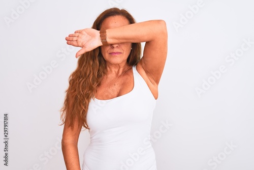 Middle age mature woman standing over white isolated background covering eyes with arm, looking serious and sad. Sightless, hiding and rejection concept