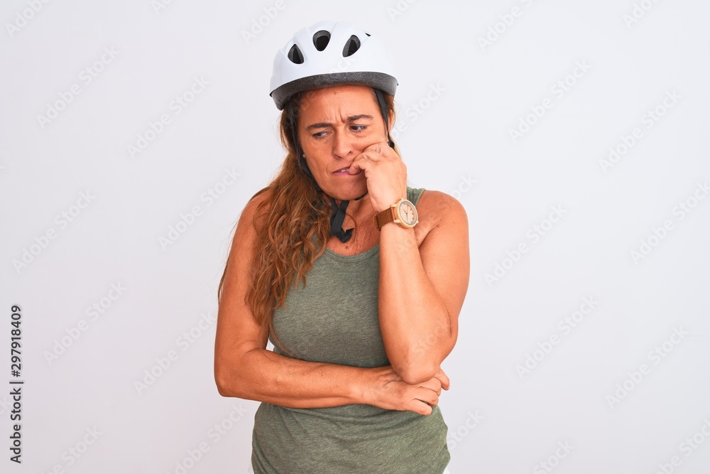 Middle age mature cyclist woman wearing safety helmet over isolated background looking stressed and nervous with hands on mouth biting nails. Anxiety problem. Middle age mature cyclist woman wearing safety helmet over isolated background looking stressed and nervous with hands on mouth biting nails. Anxiety problem.