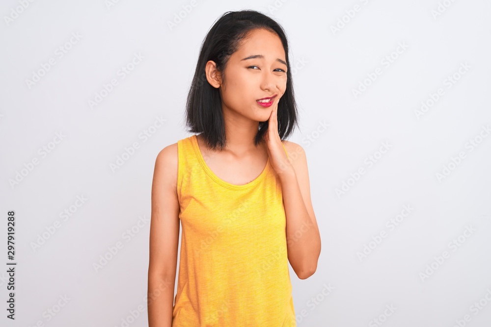 Young chinese woman wearing yellow casual t-shirt standing over isolated white background touching mouth with hand with painful expression because of toothache or dental illness on teeth. Young chinese woman wearing yellow casual t-shirt standing over isolated white background touching mouth with hand with painful expression because of toothache or dental illness on teeth.