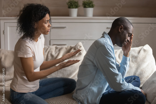 Stressed young african ethnicity woman apologizing to offended husband. photo