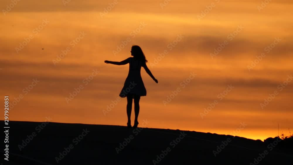 Merry girl spin at top, shadow figure against orange sunset sky. Happy woman express good emotions in simple dance. Nice vivid colour of afterglow on backdrop Merry girl spin at top, shadow figure against orange sunset sky. Happy woman express good emotions in simple dance. Nice vivid colour of afterglow on backdrop