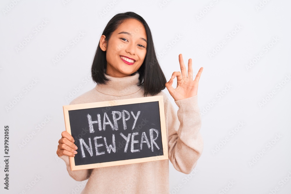 Young beautiful chinese woman holding blackboard over isolated white background doing ok sign with fingers, excellent symbol Young beautiful chinese woman holding blackboard over isolated white background doing ok sign with fingers, excellent symbol