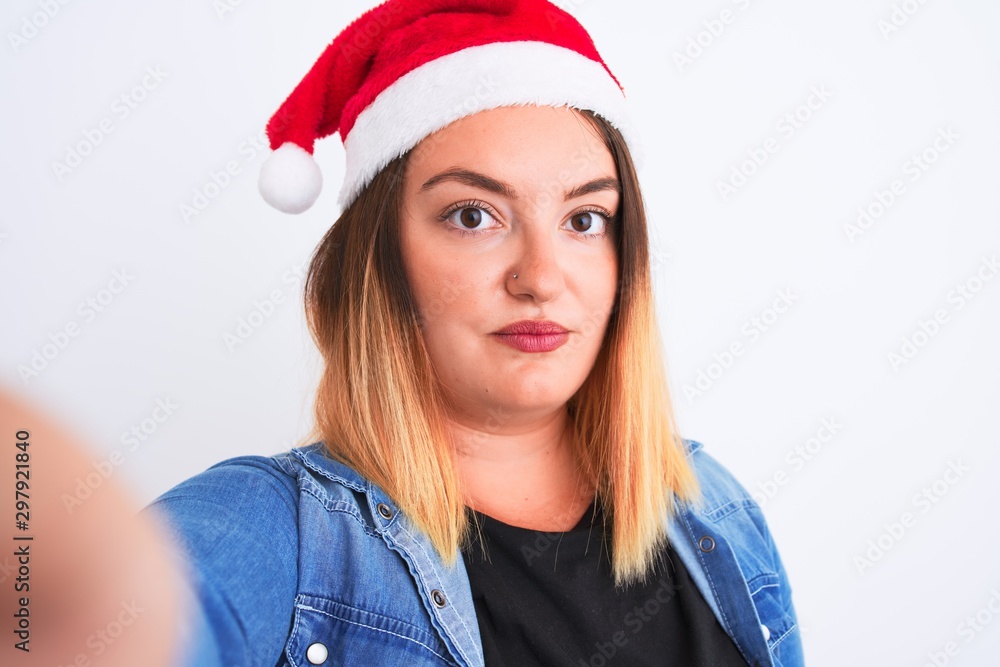 Beautiful woman wearing Christmas Santa hat make selfie over isolated white background with a confident expression on smart face thinking serious Beautiful woman wearing Christmas Santa hat make selfie over isolated white background with a confident expression on smart face thinking serious