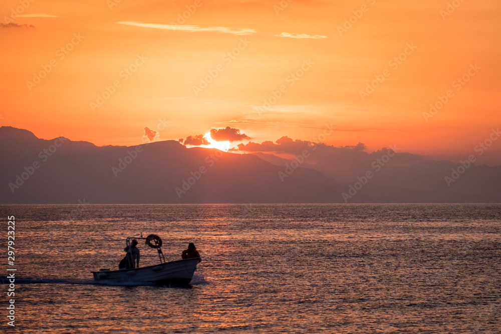 Fishing boat sailing in the sunset over the Mediterranean Sea in Cefalu, Sicily