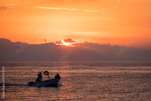 Fishing boat sailing in the sunset over the Mediterranean Sea in Cefalu, Sicily