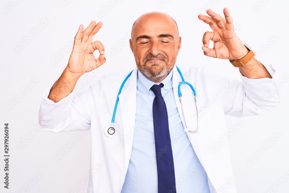 Middle age doctor man wearing stethoscope and tie standing over isolated white background relax and smiling with eyes closed doing meditation gesture with fingers. Yoga concept. Middle age doctor man wearing stethoscope and tie standing over isolated white background relax and smiling with eyes closed doing meditation gesture with fingers. Yoga concept.