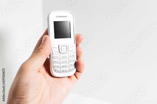 Male hand holding old cell phone isolated on white background.