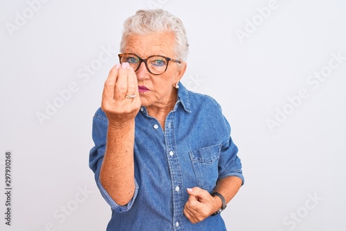 Senior grey-haired woman wearing denim shirt and glasses over isolated white background Doing Italian gesture with hand and fingers confident expression