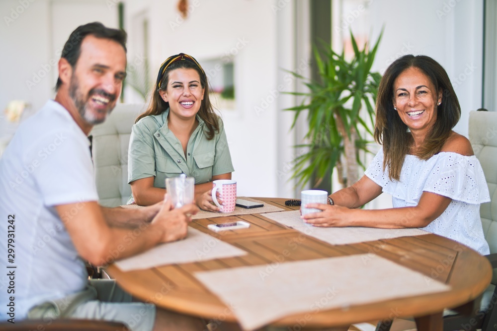 Beautiful family sitting on terrace drinking cup of coffee speaking and smiling Beautiful family sitting on terrace drinking cup of coffee speaking and smiling