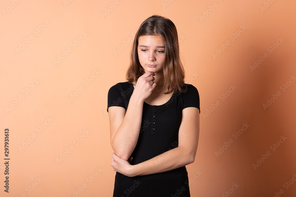 The girl thought and looks up, on a light orange background. The girl thought and looks up, on a light orange background.