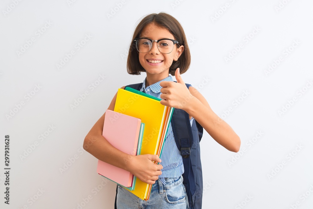 Beautiful student child girl wearing backpack glasses books over isolated white background happy with big smile doing ok sign, thumb up with fingers, excellent sign Beautiful student child girl wearing backpack glasses books over isolated white background happy with big smile doing ok sign, thumb up with fingers, excellent sign