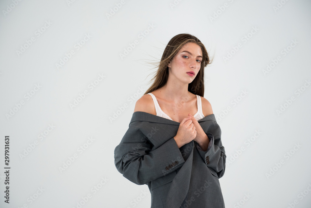 Young girl in trench coat with hat on gray background