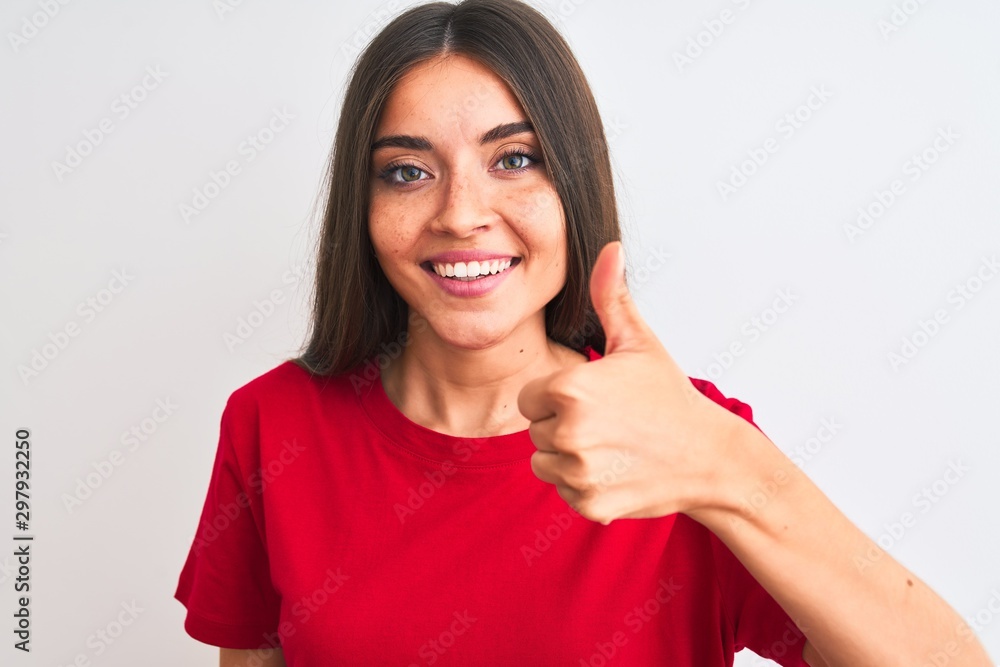 Young beautiful woman wearing red casual t-shirt standing over isolated white background happy with big smile doing ok sign, thumb up with fingers, excellent sign Young beautiful woman wearing red casual t-shirt standing over isolated white background happy with big smile doing ok sign, thumb up with fingers, excellent sign