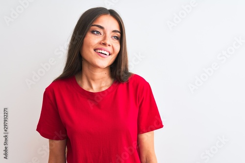 Young beautiful woman wearing red casual t-shirt standing over isolated white background looking away to side with smile on face, natural expression. Laughing confident. © Krakenimages.com