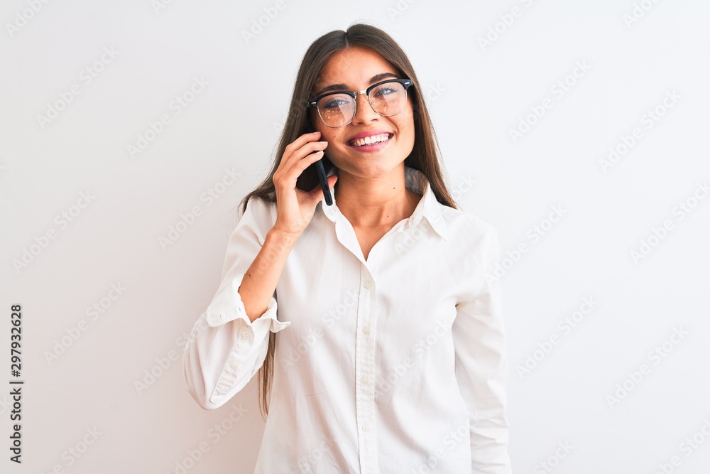 Young businesswoman wearing glasses talking on smartphone over isolated white background with a happy face standing and smiling with a confident smile showing teeth Young businesswoman wearing glasses talking on smartphone over isolated white background with a happy face standing and smiling with a confident smile showing teeth