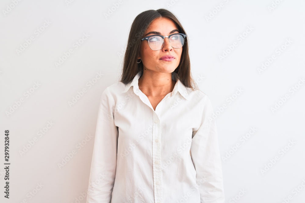 Young beautiful businesswoman wearing glasses standing over isolated white background smiling looking to the side and staring away thinking.