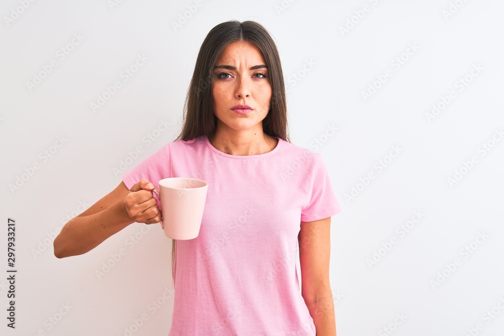 Young beautiful woman drinking pink cup of coffee standing over isolated white background with a confident expression on smart face thinking serious Young beautiful woman drinking pink cup of coffee standing over isolated white background with a confident expression on smart face thinking serious
