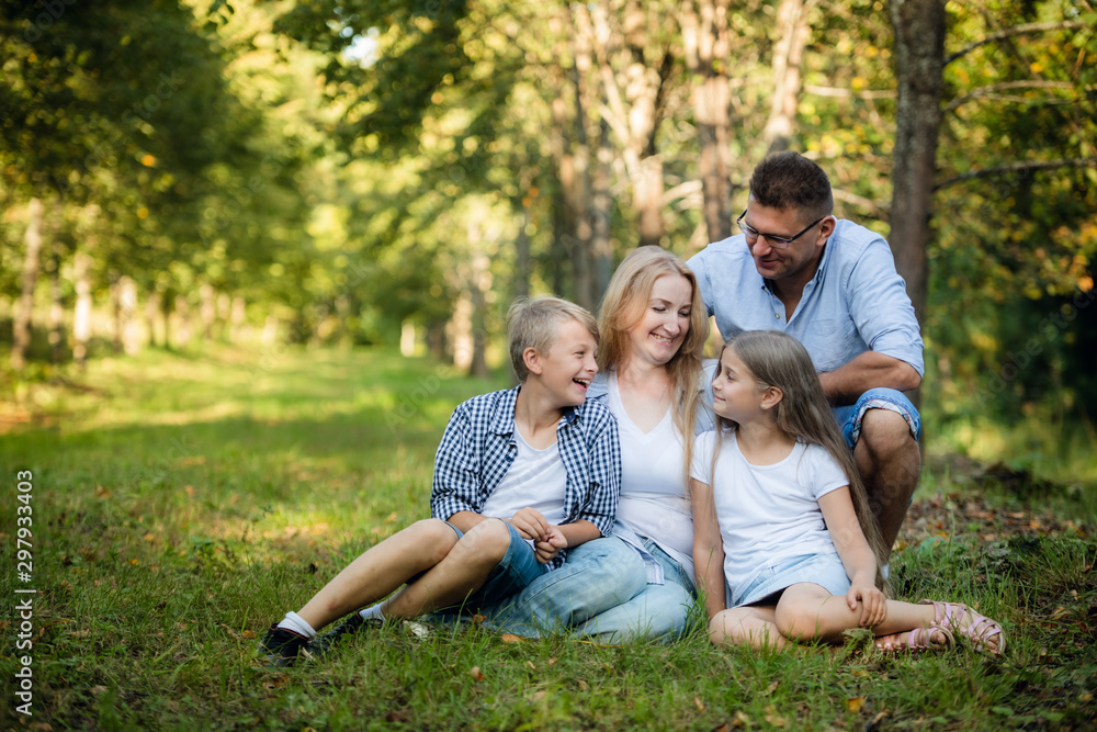Portrait of happy family of four in a green summer park