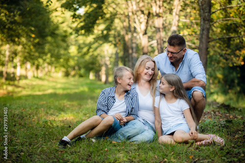 Portrait of happy family of four in a green summer park