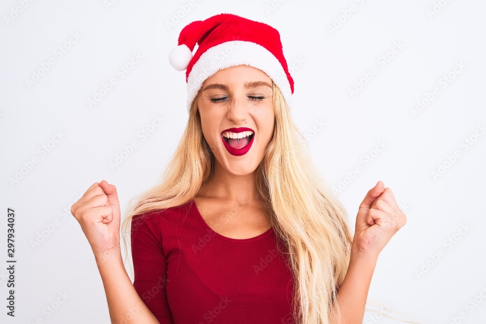 Young beautiful woman wearing Christmas Santa hat over isolated white background excited for success with arms raised and eyes closed celebrating victory smiling. Winner concept. Young beautiful woman wearing Christmas Santa hat over isolated white background excited for success with arms raised and eyes closed celebrating victory smiling. Winner concept.
