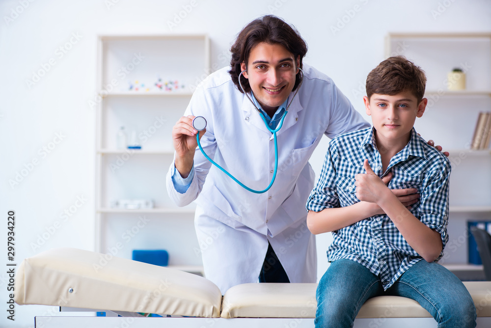Fototapeta premium Male doctor examining boy by stethoscope