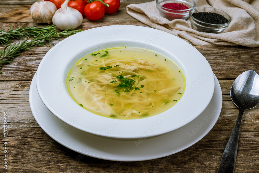 Chicken soup bouillon in a plate on wooden table
