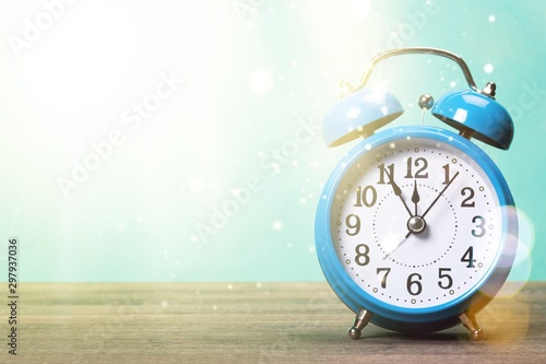 Blue retro alarm clock on wooden table on wall background