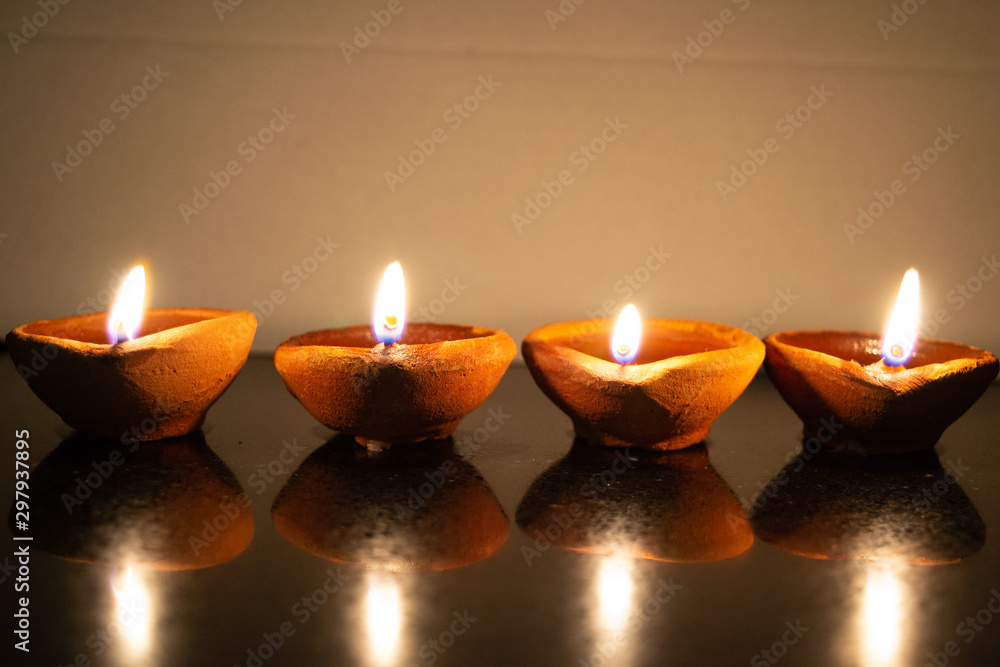 Diwali diyas lined up in a row on a reflective surface Diwali diyas lined up in a row on a reflective surface