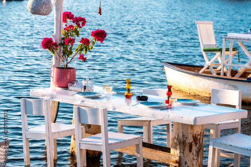 Aegean fish restaurant table in Gumusluk Town, Bodrum, Turkey. Restaurant tables and chairs are in the sea photo