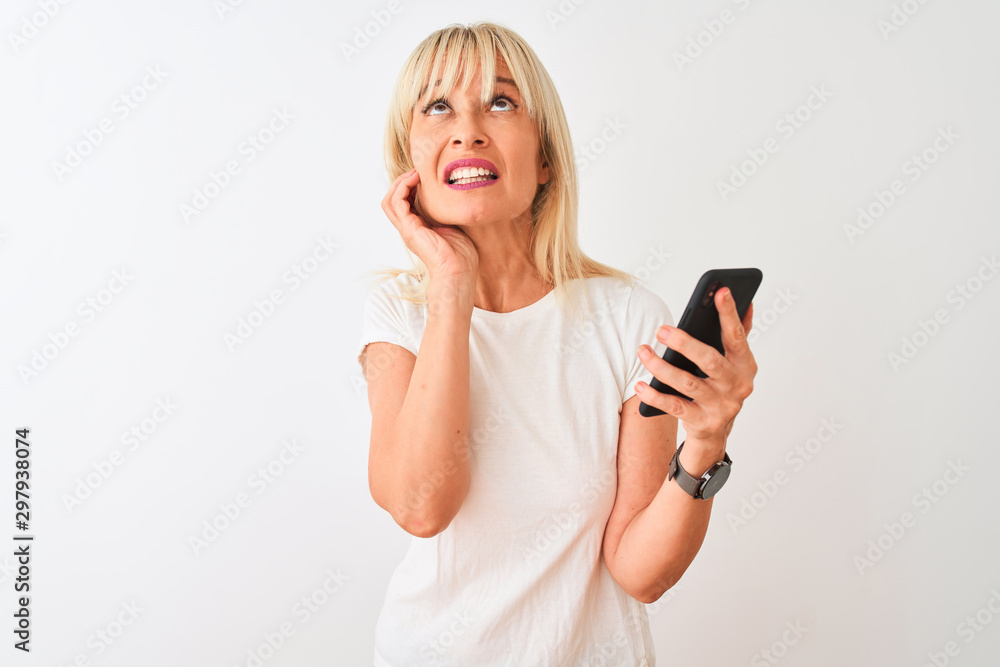 Middle age woman using smartphone standing over isolated white background serious face thinking about question, very confused idea Middle age woman using smartphone standing over isolated white background serious face thinking about question, very confused idea