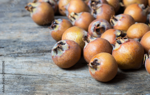 Fresh ripe organic common medlar fruit on wooden rustic background. Healthy food Mespilus germanica