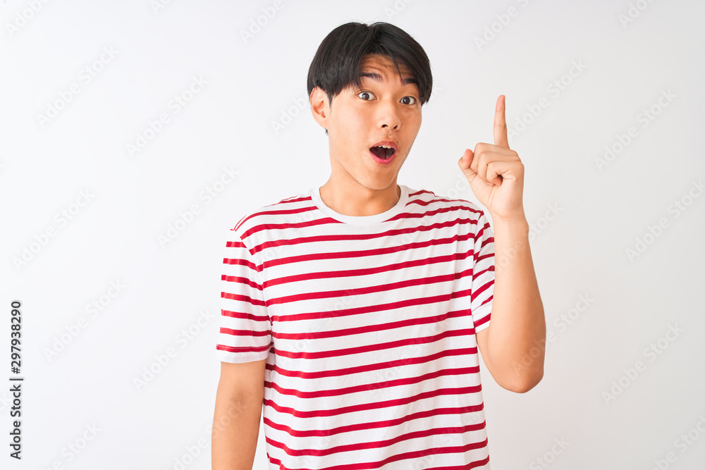 Young chinese man wearing casual striped t-shirt standing over isolated white background pointing finger up with successful idea. Exited and happy. Number one. Young chinese man wearing casual striped t-shirt standing over isolated white background pointing finger up with successful idea. Exited and happy. Number one.