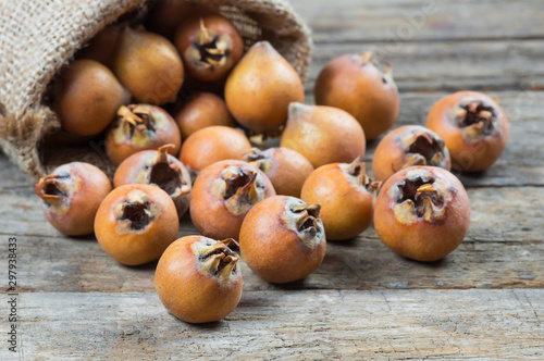 Fotografía Fresh ripe organic common medlar fruit in burlap sack on wooden rustic background