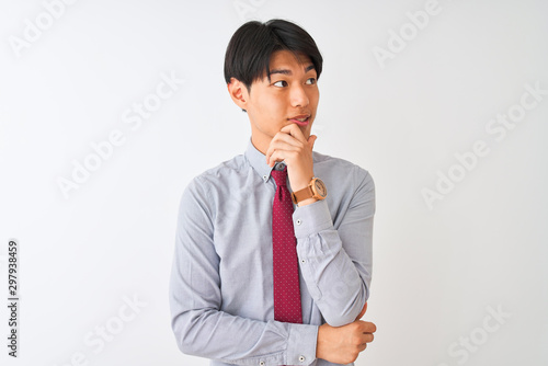Chinese businessman wearing elegant tie standing over isolated white background with hand on chin thinking about question, pensive expression. Smiling and thoughtful face. Doubt concept.