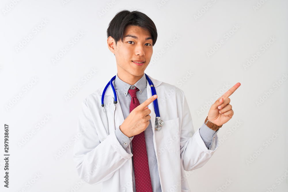 Chinese doctor man wearing coat tie and stethoscope over isolated white background smiling and looking at the camera pointing with two hands and fingers to the side. Chinese doctor man wearing coat tie and stethoscope over isolated white background smiling and looking at the camera pointing with two hands and fingers to the side.