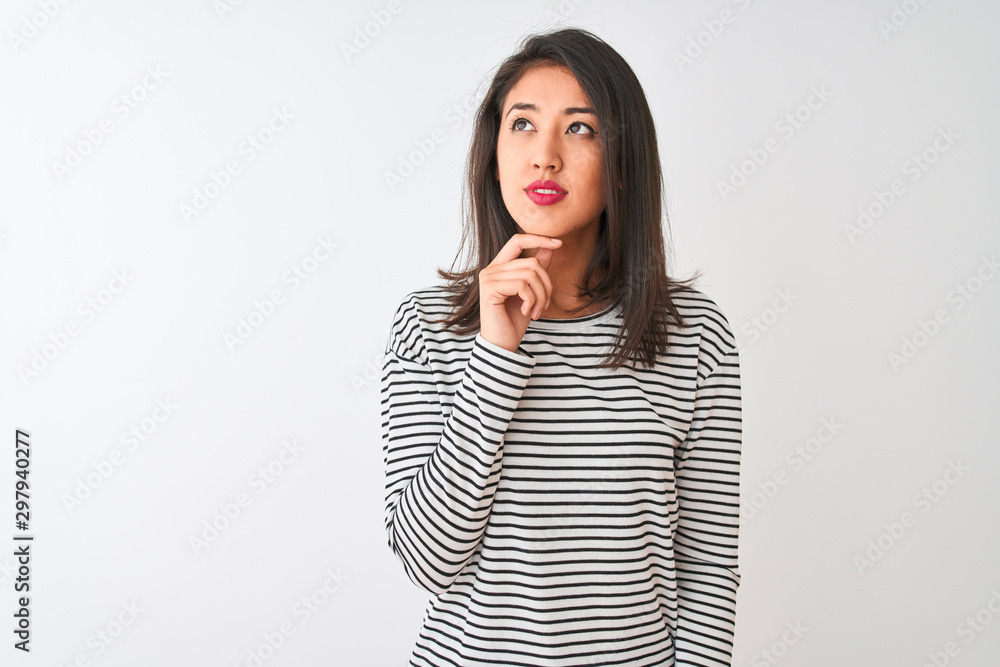 Young beautiful chinese woman wearing striped t-shirt standing over isolated white background with hand on chin thinking about question, pensive expression. Smiling with thoughtful face. Doubt concept Young beautiful chinese woman wearing striped t-shirt standing over isolated white background with hand on chin thinking about question, pensive expression. Smiling with thoughtful face. Doubt concept